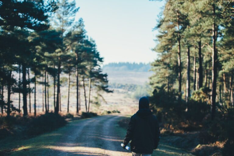 person wearing jacket walking on dirt road